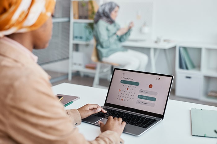 Woman working on laptop in office, using time management software